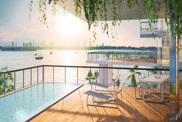 Modern waterfront terrace with a rectangular pool, sun loungers, and a dining table, overlooking boats and a city skyline at sunset.